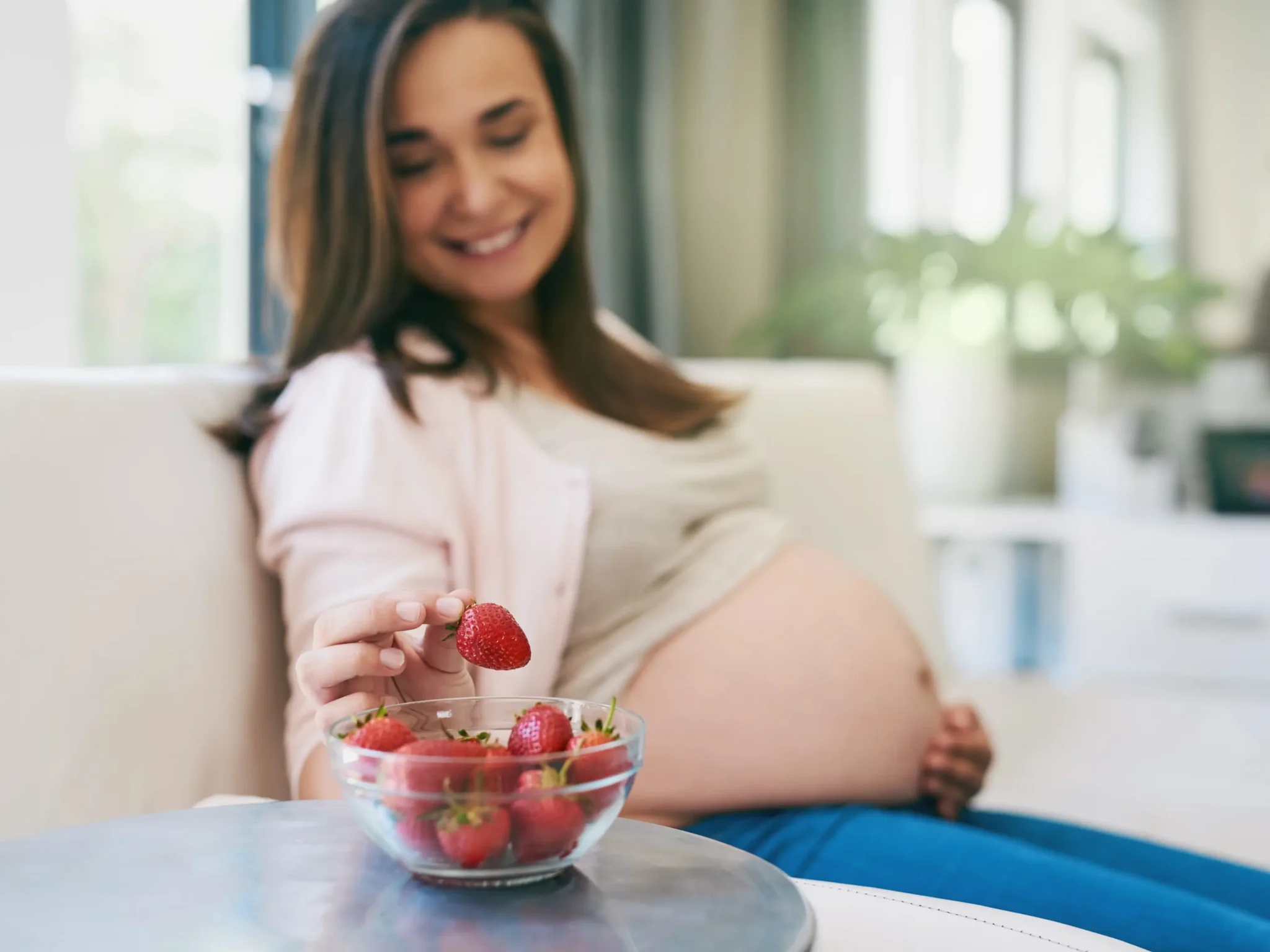 donna in gravidanza che mangia delle fragole, è importante consumare frutta e verdura ogni giorno in gravidanza