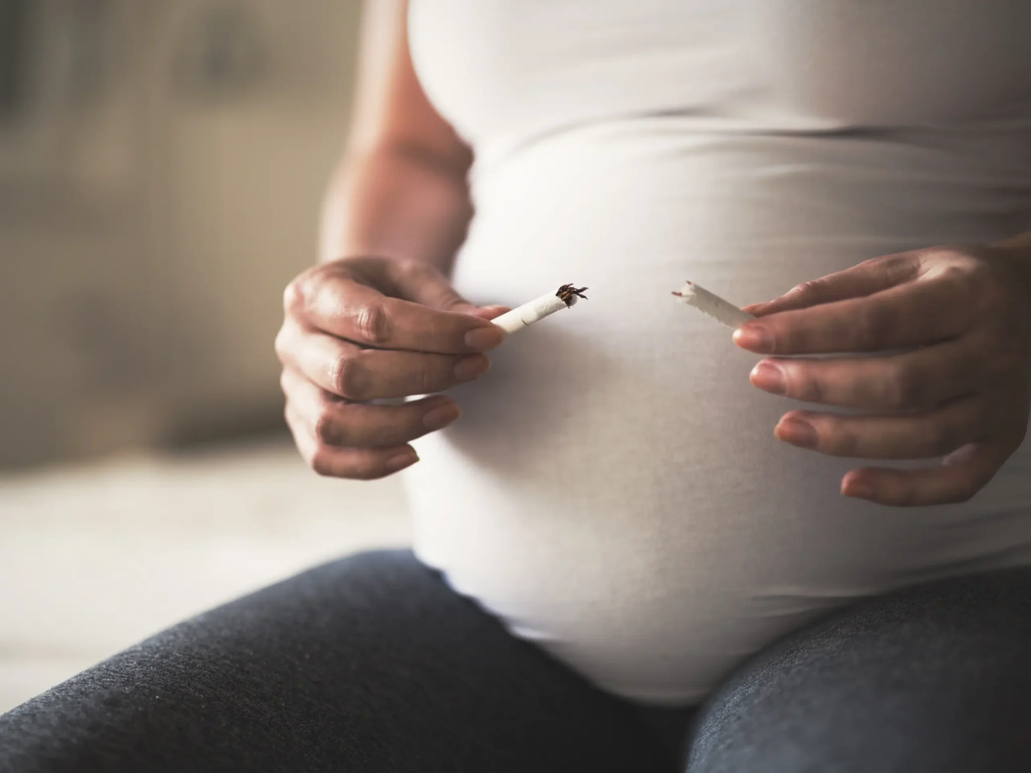 donna in gravidanza che spezza una sigaretta, evitare il fumo in gravidanza per evitare conseguenze dannose