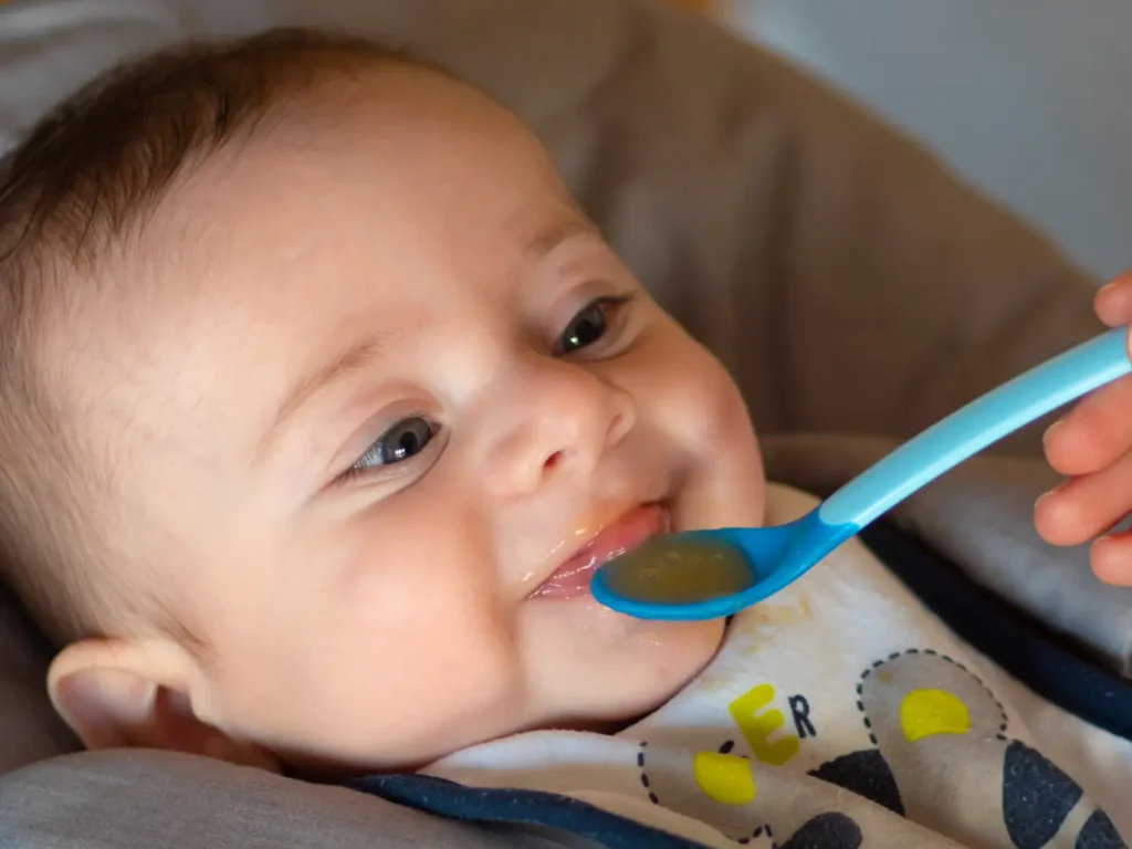 bambino che inizia lo svezzamento consumando puree di frutta e verdura, lo svezzamento a 4 mesi