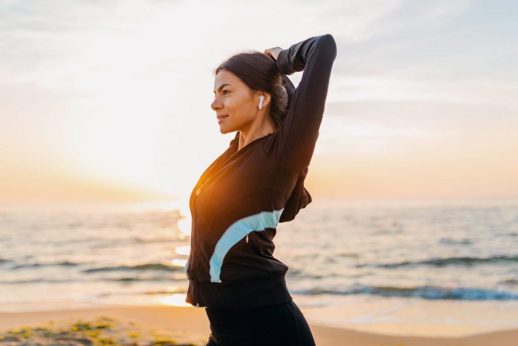 Donna che svolge attività fisica in spiaggia per contrastare patologia autoimmune
