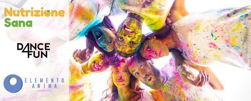 Si vedono a sinistra i loghi di Nutrizione Sana, Dance4Fun ed Elemanto Anima, a destra un gruppo di ragazzi fra i 15 e i 25 anni che si dispongono in cerchio dopo essersi cosparsi della polvere colorata addosso e sul viso.