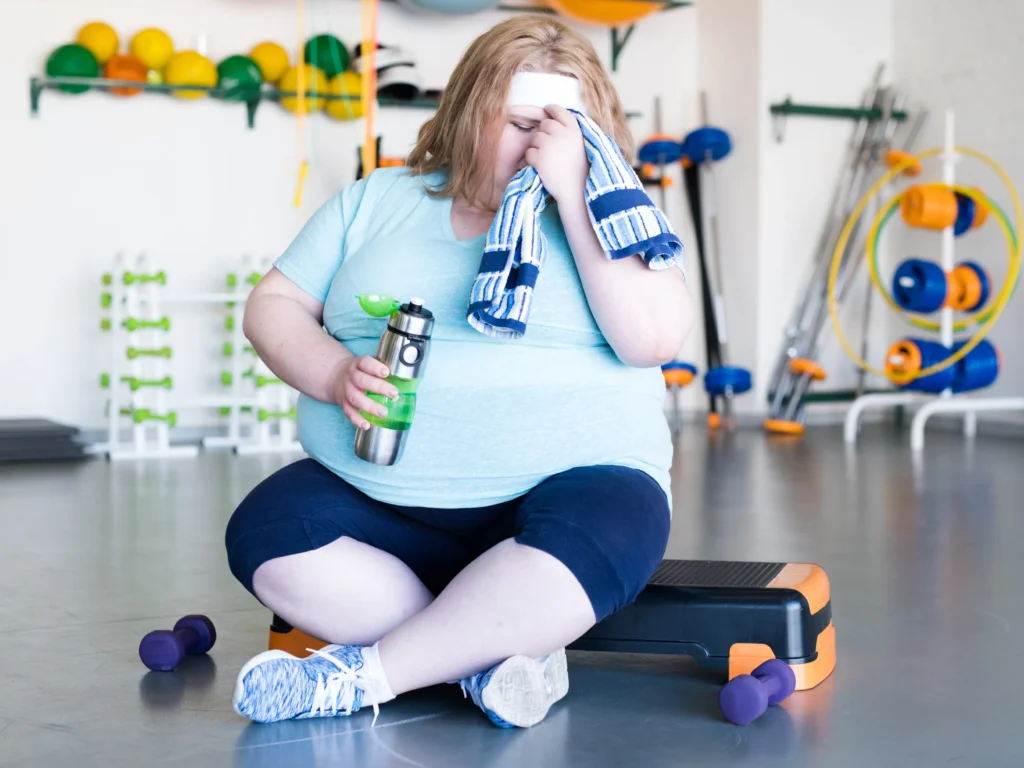 ragazza con patologia di obesità stanca in palestra, importanza dell'alimentazione in adolescenza per evitare patologie come obesità