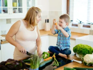 mamma e figlio che consumano ortaggi e frutta, ricche di numerosi nutrienti, vitamine e minerali che vengono trasmessi attraverso il latte materno, importanti durante l'allattamento