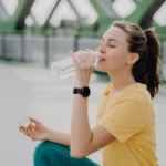 donna che beve acqua dalla bottiglia, evitare l'acqua dal rubinetto se si soffre di allergia al nichel