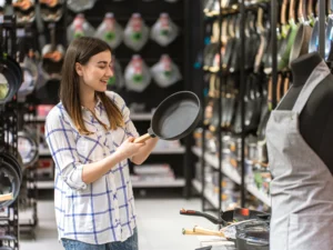 ragazza che compra utensili da cucina senza nichel per chi soffre di allergia al nichel. Gli utensili da cucina, le pentole, le posate ed i contenitori per alimenti se contengono nichel potrebbero rilasciarlo nel cibo