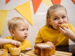 bambini che mangiano dolci ad una festa, importante consumare grassi saturi con moderazione per alimentazione in infanzia