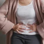 donna con gonfiore addominale, bruciore e nausea, è importante smettere di mangiare non appena ci si senti sazi, in menopausa