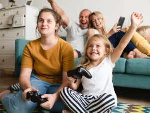 bambine che giocano ai videogame con i genitori, limitare l'utilizzo di videogame e televisione ad un massimo di 2 ore al giorno durante l'infanzia